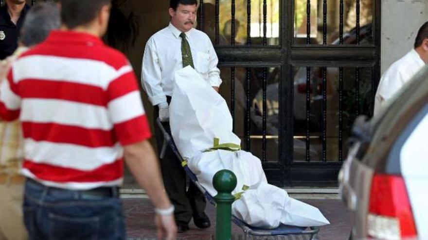 Un trabajador de la funeraria traslada el cuerpo de la mujer asesinada, ayer en Málaga. / efe