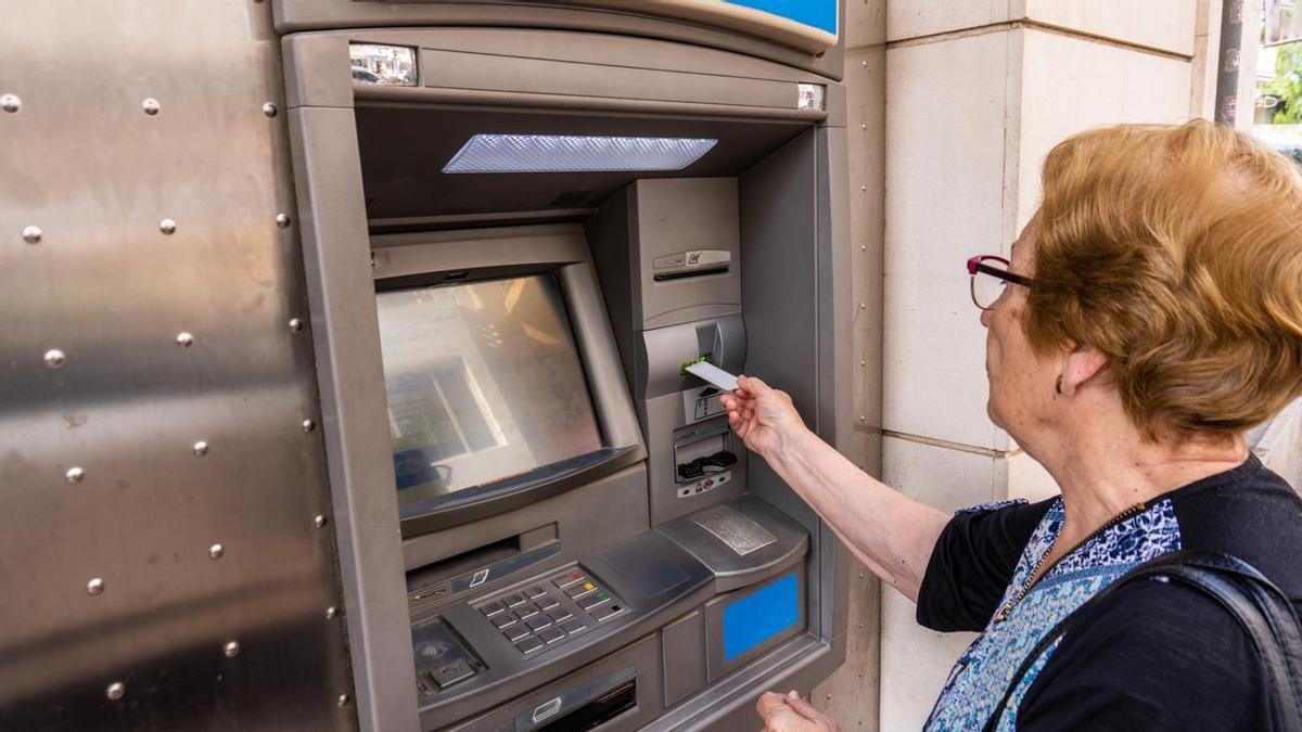 Una mujer saca dinero de un cajero.