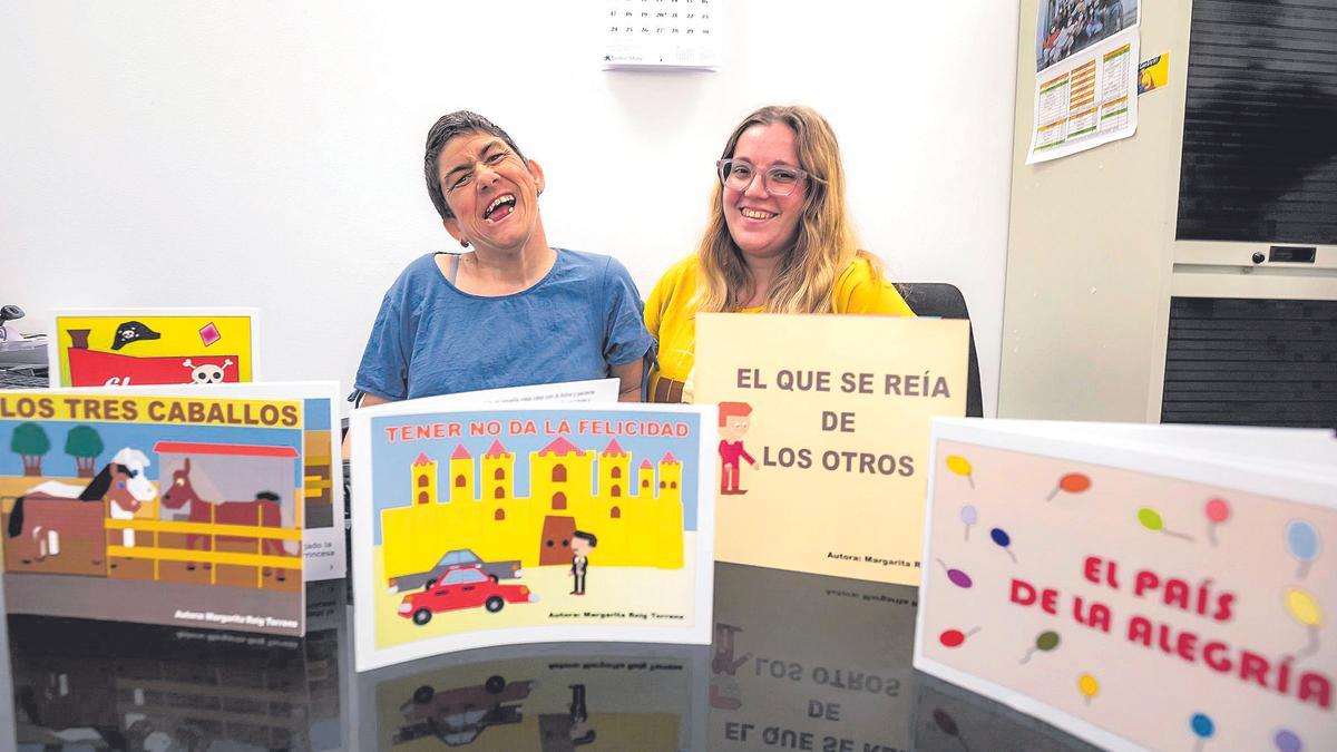 Marga Roig posa junto a su acompañante Sheila Pereira y algunos de sus libros publicados en la sede de Aspaym