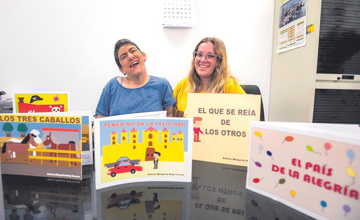 Marga Roig posa junto a su acompañante Sheila Pereira y algunos de sus libros publicados en la sede de Aspaym