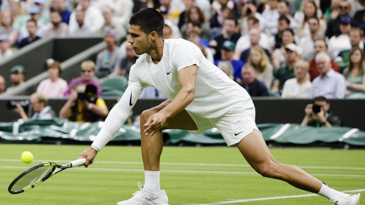 Carlos Alcaraz realiza un golpe de revés en su partido de primera ronda en Wimbledon.