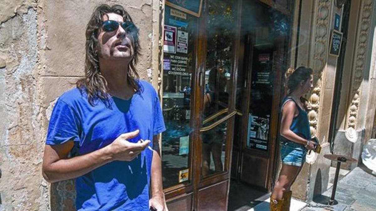 Dos personas fuman junto a la puerta de un establecimiento de Barcelona, ayer.