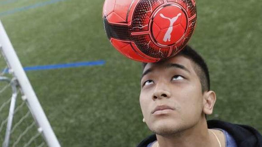 Vítor Ono sostiene un balón sobre la cabeza.