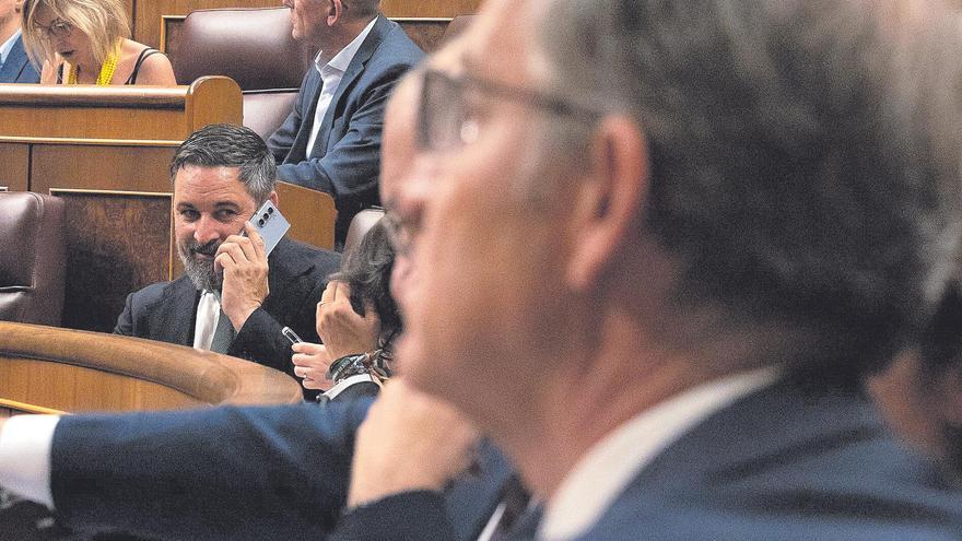 El líder de Vox hablando por teléfono, durante un Pleno extraordinario en el Congreso. En primer término, Alberto Núñez Feijóo.