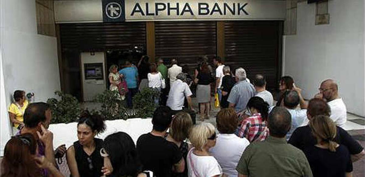 Desenes de persones fan cua per treure diners d’un banc a Atenes.