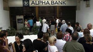 Decenas de personas hacen cola para sacar dinero de un banco en Atenas.