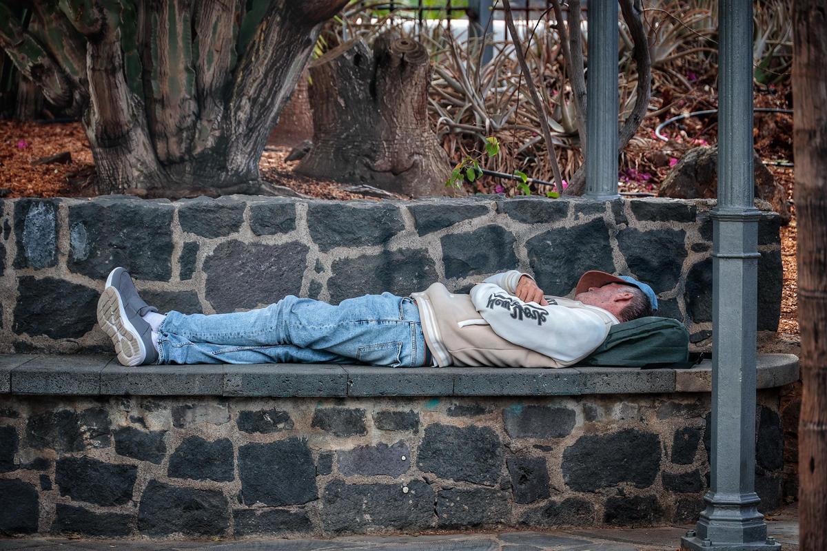 Una persona sin hogar duerme en un banco, en el municipio de Santa Cruz de Tenerife.