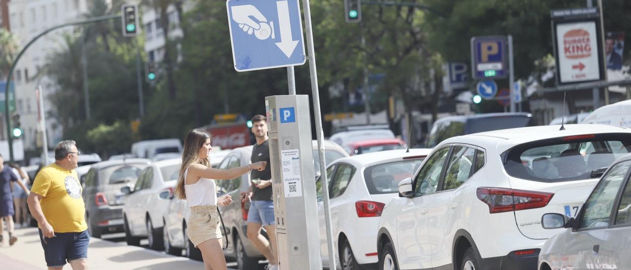 Una mujer echa monedas en un parquímetro de la zona azul en Córdoba.