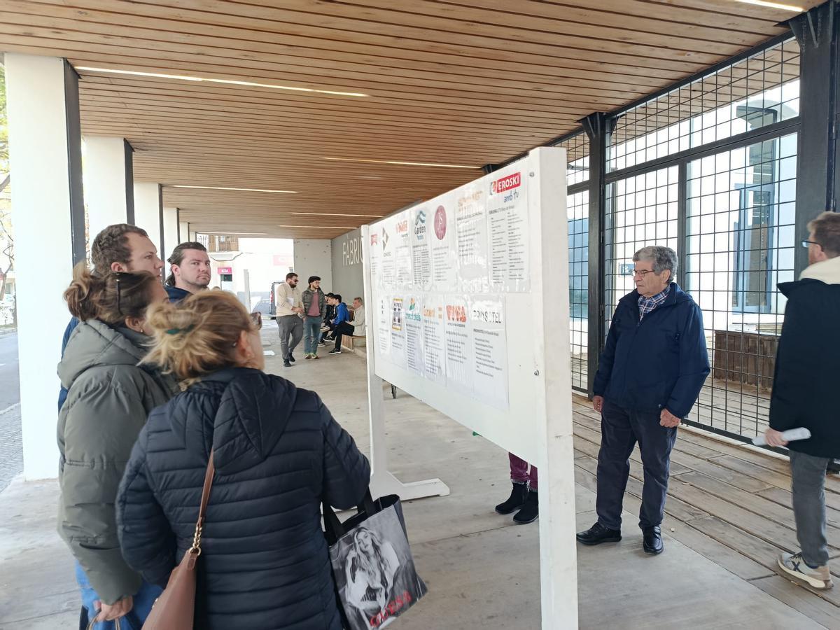 Varias personas miran las plazas laborales que se ofertan en los paneles exteriores de la Fàbrica Ramis.