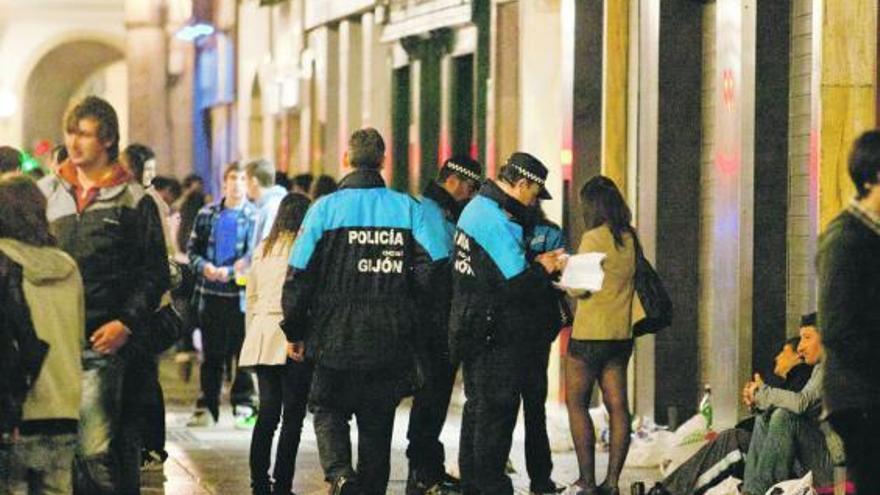 Agentes de la Policía Local, el sábado por la noche, en Marqués de San Esteban, junto a jóvenes que consumen alcohol.