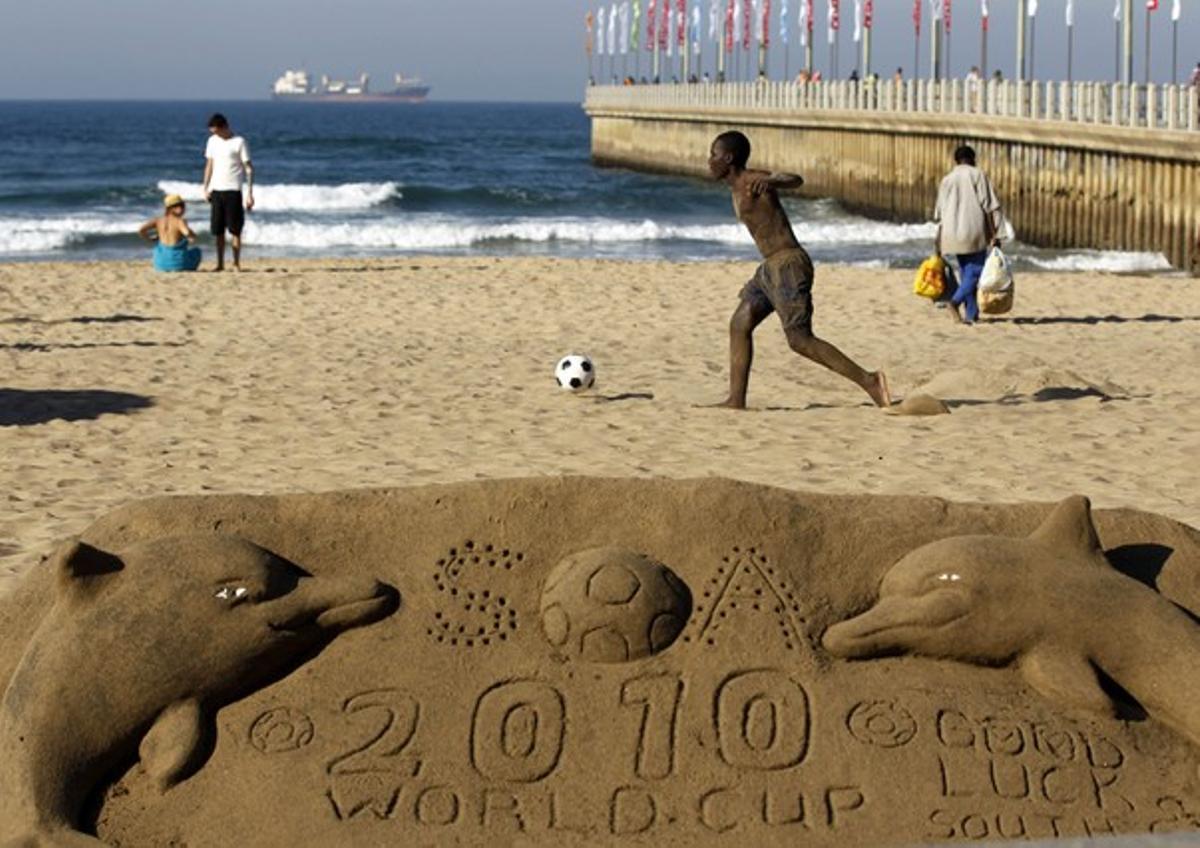 Un nen juga a futbol a la platja de Durban.