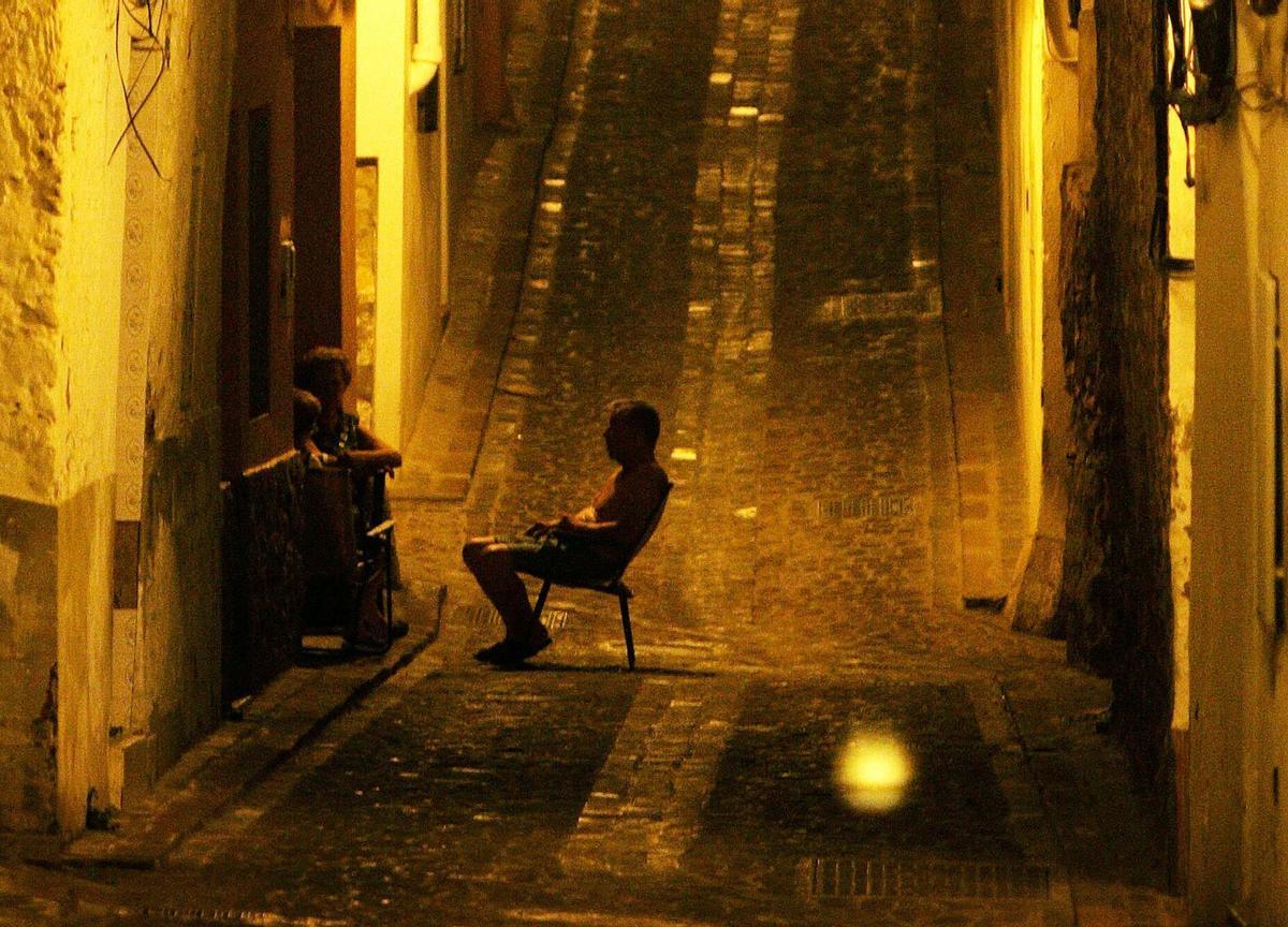 Varias personas toman el fresco por la noche en una calle del casco antiguo de Sagunto (Valencia).