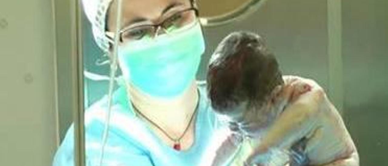 Una doctora agarrando a un recién nacido en un parto.