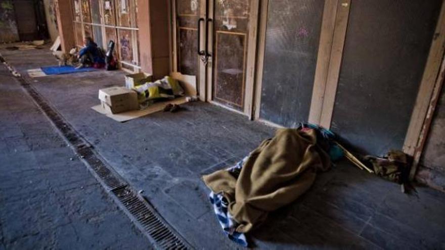 Personas sin hogar duermen en los soportales de la plaza de San Cristóbal, en la ciudad de Alicante.