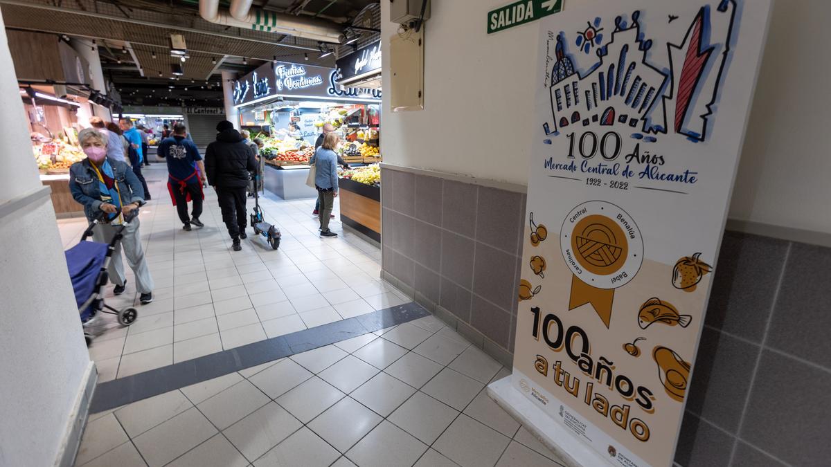 Varios consumidores junto a un cartel del centenario.