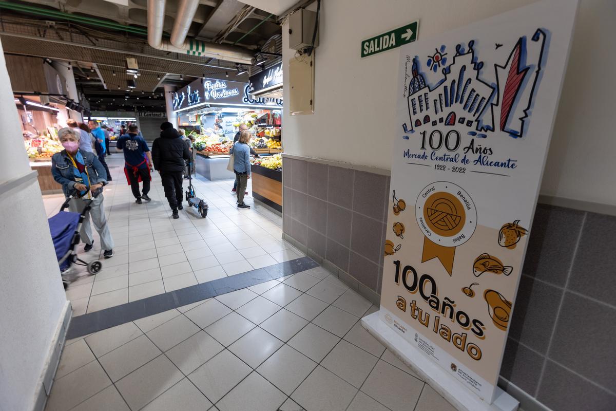 Varios consumidores junto a un cartel del centenario.