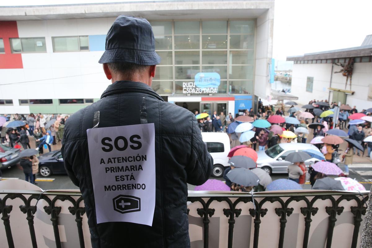 Uno de los participantes en la concentración con un cartel de protesta en su espalda.