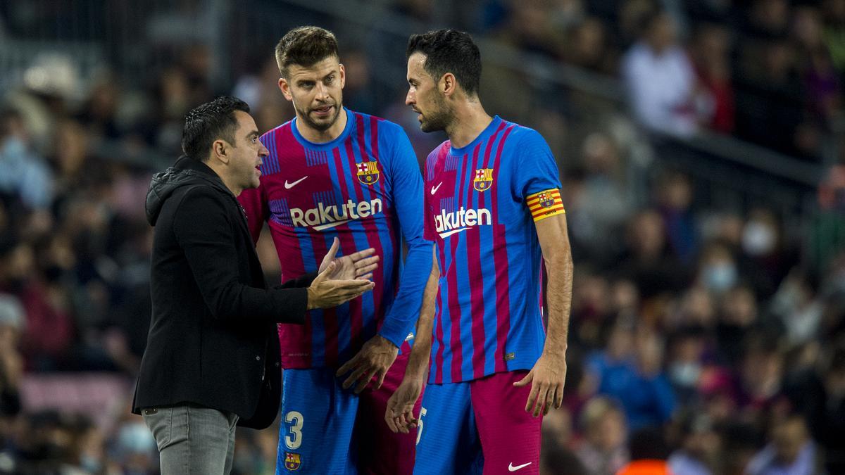 Xavi se dirige a Piqué y Busquets en la banda durante el partido de liga entre el FC Barcelona y el RCD Espanyol en el Camp Nou, en noviembre de 2021.
