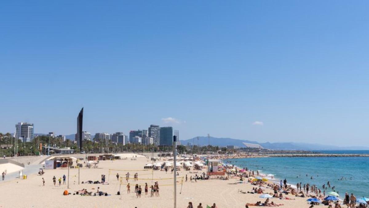 Bañistas en la arena y nadando en la playa del Bogatell vistos desde el espigón del Bogatell