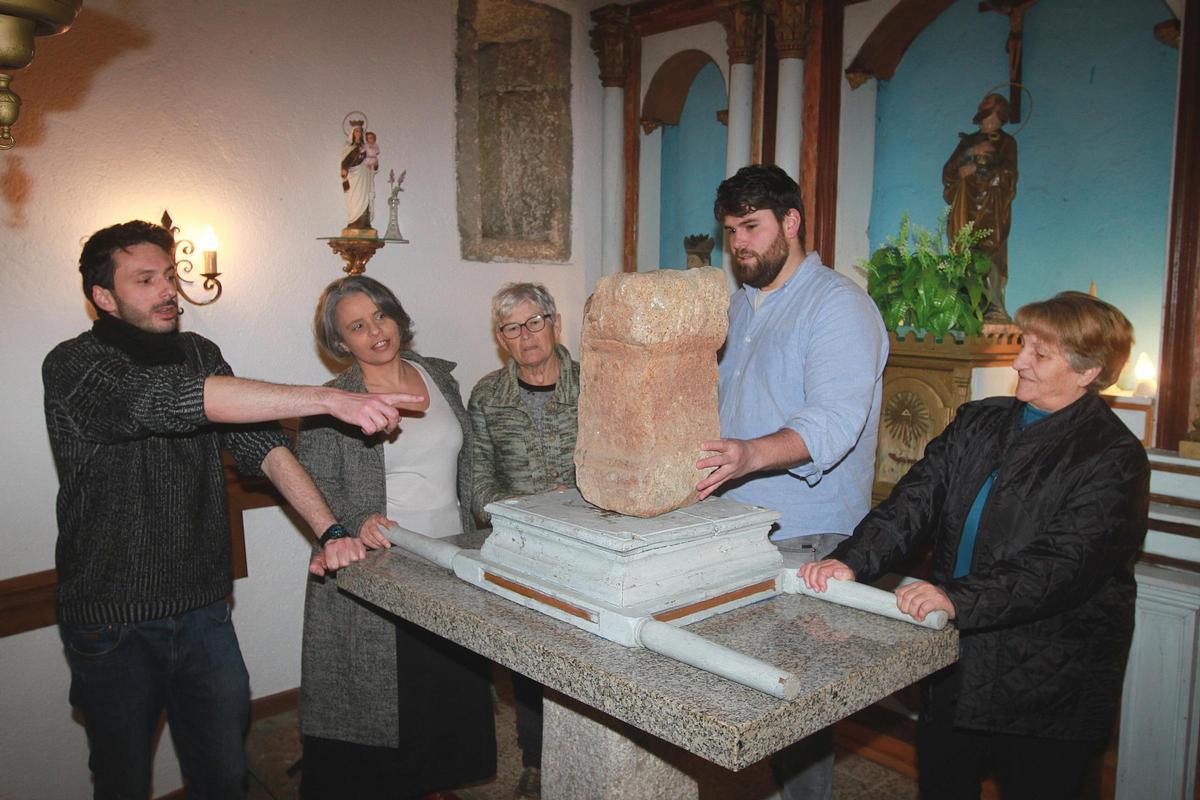 El ara romana, bajo la mirada atenta de dos vecinas y tres miembros de Amigos do Patrimonio de Toén.