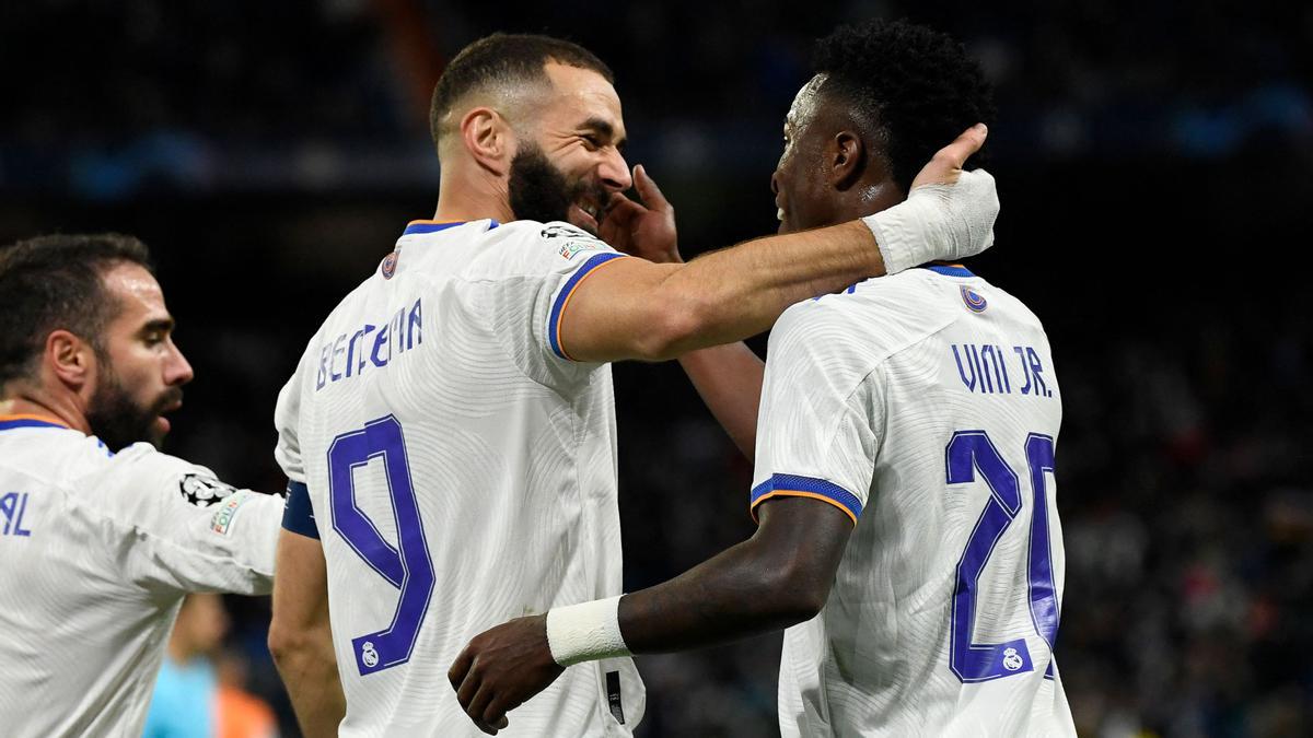 Real Madrid's French forward Karim Benzema (C) celebrates with Real Madrid's Brazilian forward Vinicius Junior (R) after scoring his team's second goal during the UEFA Champions League first round group D football match between Real Madrid CF and Shakhtar Donetsk at the Santiago Bernabeu stadium in Madrid on November 3, 2021. (Photo by PIERRE-PHILIPPE MARCOU / AFP)