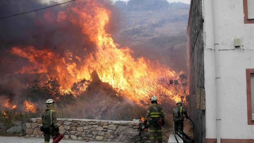 Unos bomberos realizan una quema controlada cerca de una casa en Carnota. | Lavandeira Jr./Efe