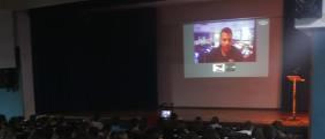 Los alumnos siguen la videoconferenica en el salón de actos.