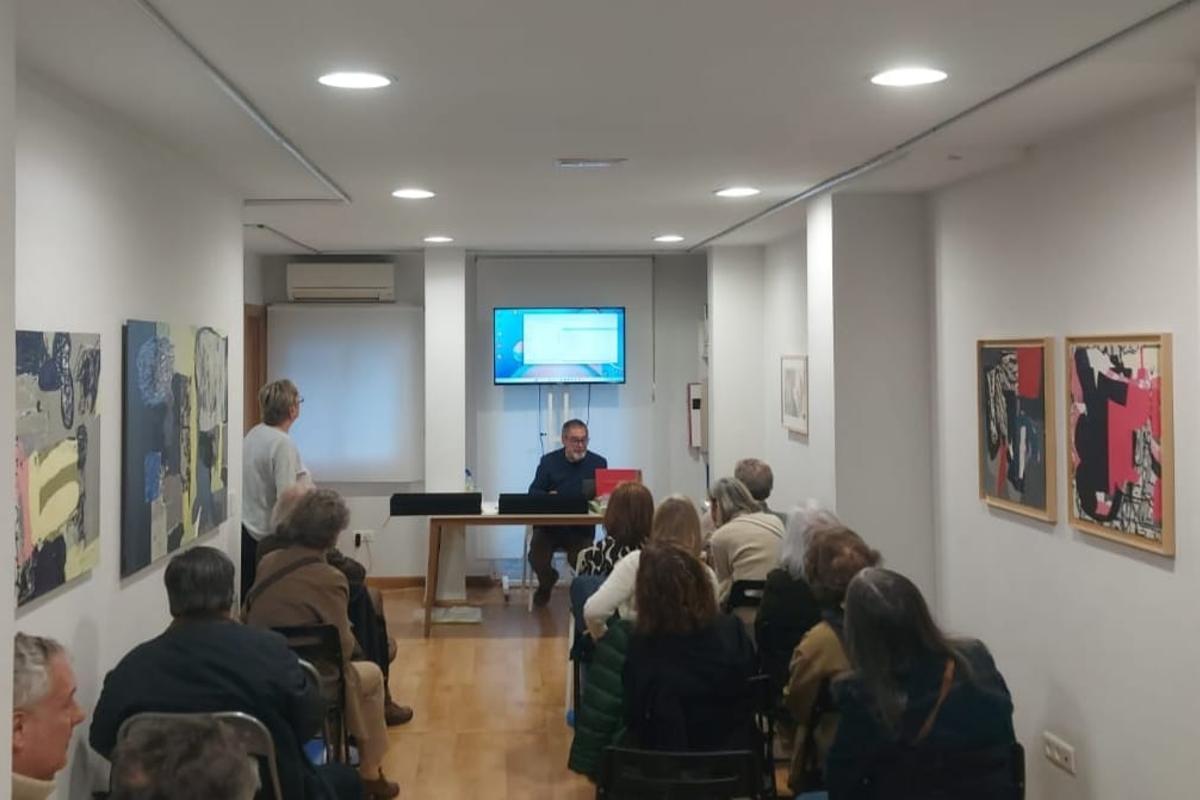 Carlos Piñel, al fondo, en una presentación de uno de los libros de autor en la sala que luce sus cuadros.