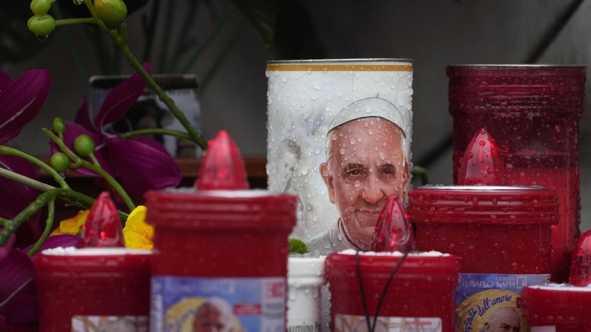 La lluvia cae sobre las velas auspiciosas con imágenes del Papa Francisco.