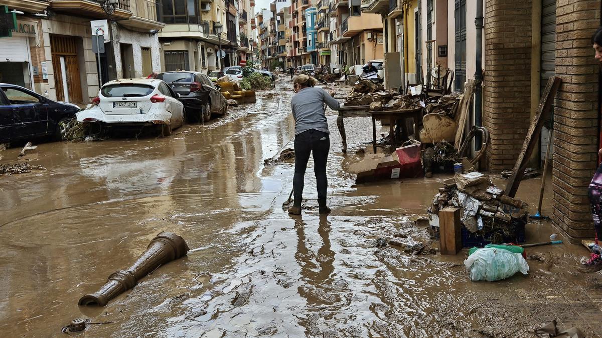 Una mujer limpia una calle de Algemesí tras la dana, en una imagen de archivo.