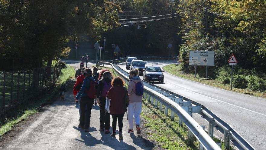 Un grup d'excursionistes camina en direcció a la Fageda d'en Jordà aquest dissabte 24 d'octubre després d'haver aparcat en una urbanització.