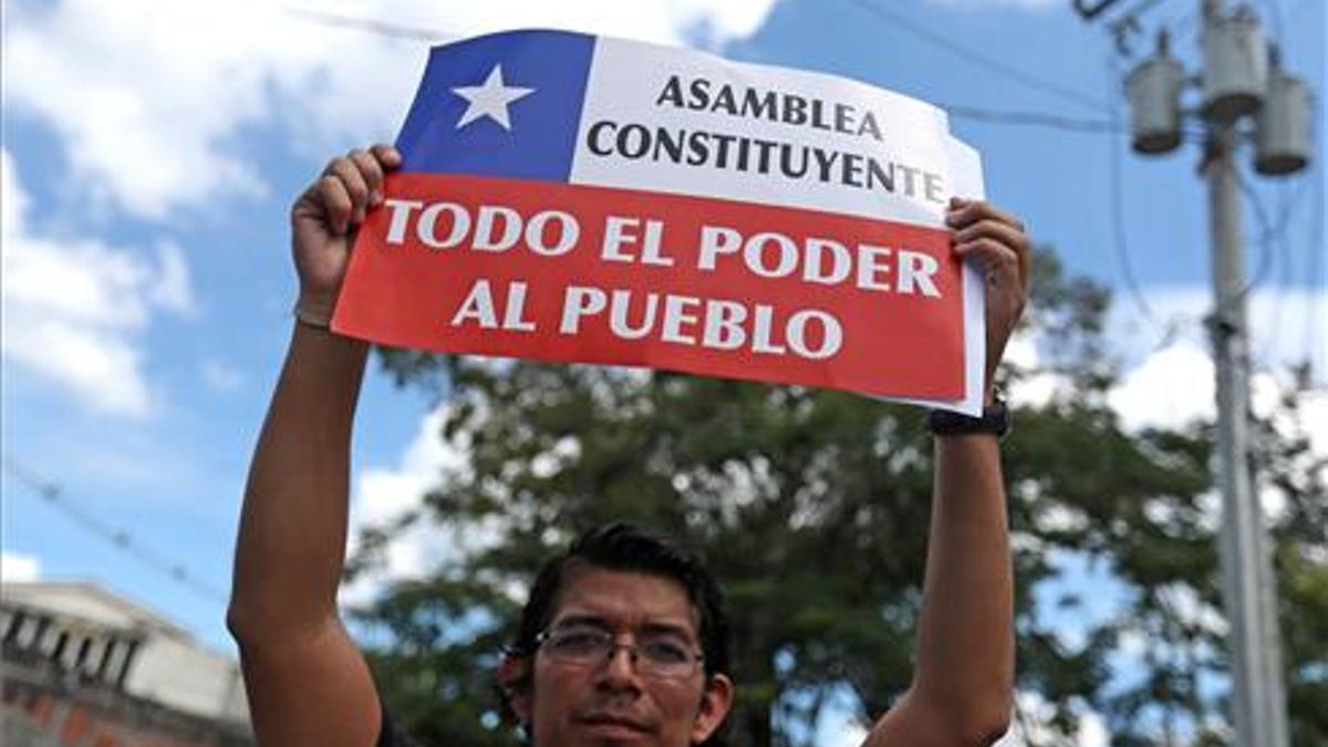 Un hombre se manifiesta en apoyo a las protestas chilenas y a una nueva Constitución frente a la Embajada de Chile en El Salvador.