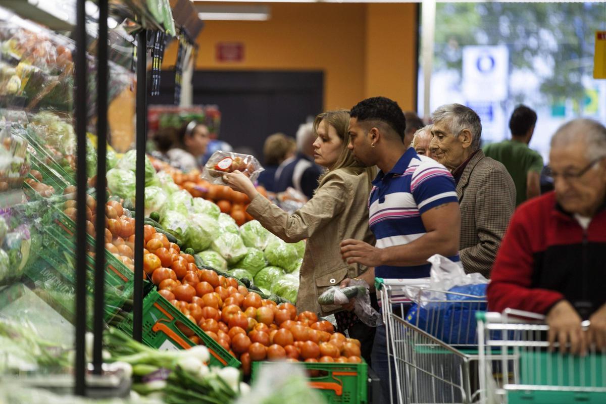 Varias personas realizan la compra en un supermercado.