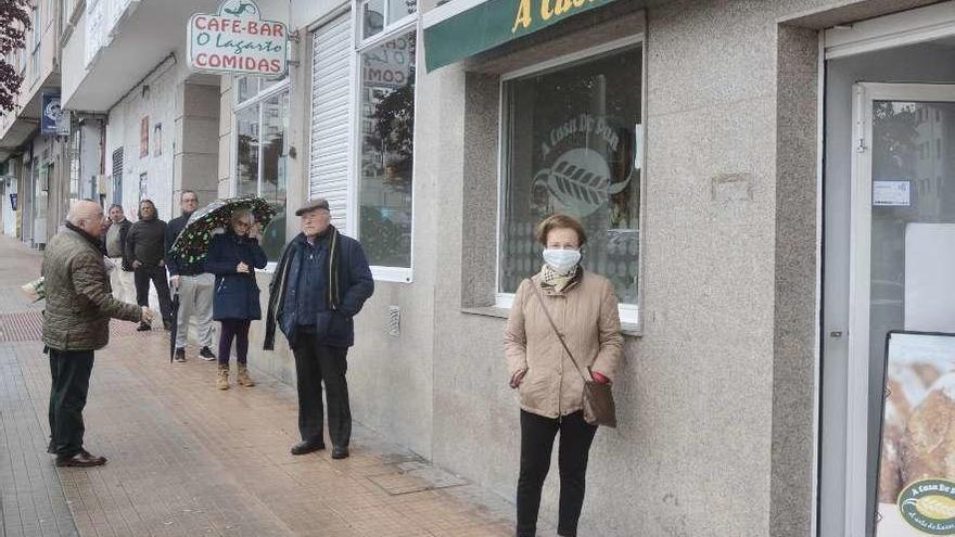 Varios vecinos de Pontevedra, a la cola y guardando la distancia ante una panadería. // Rafa Vázquez