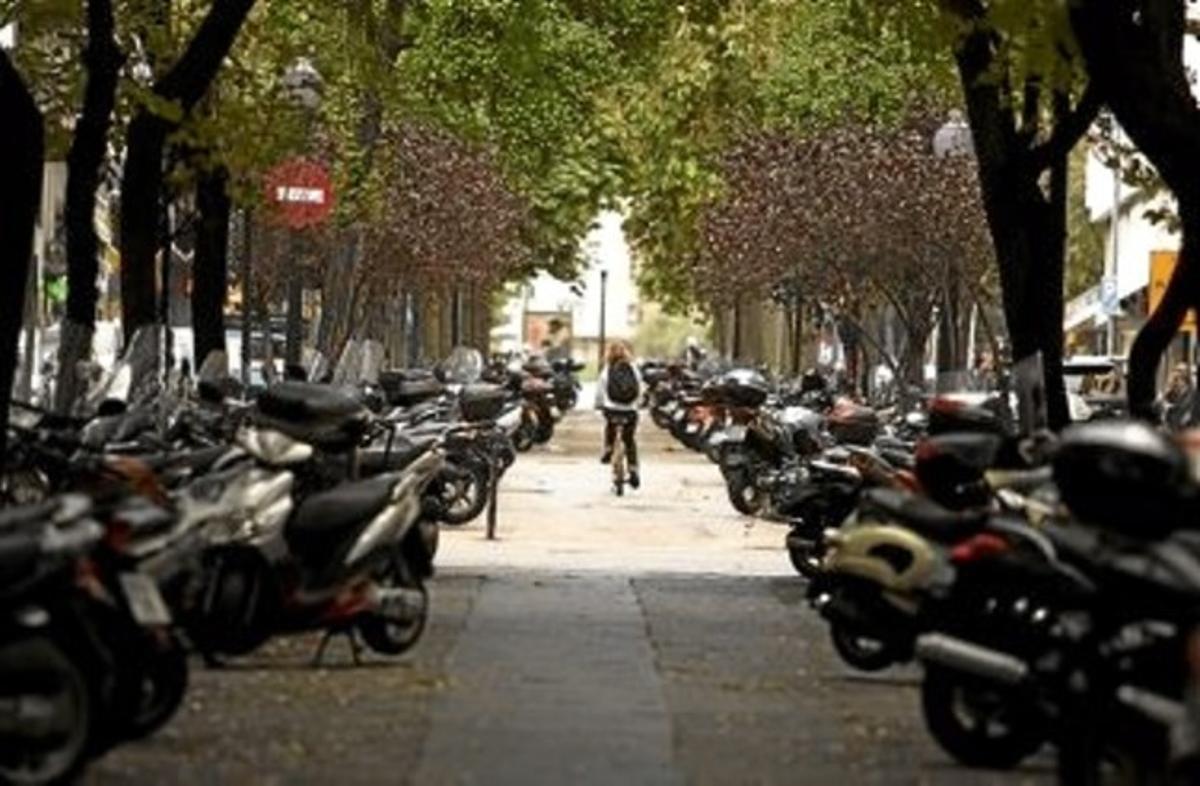 Una cliclista circula per la Via Augusta, ocupada per les motos aparcades, ahir. Una cliclista circula per la Via Augusta, ocupada per les motos aparcades, ahir.