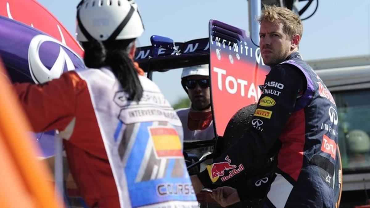 Vettel ayuda a subir su coche a la grúa tras poder completar solo cuatro vueltas en los entrenamientos matutinos del circuito de Montmeló.