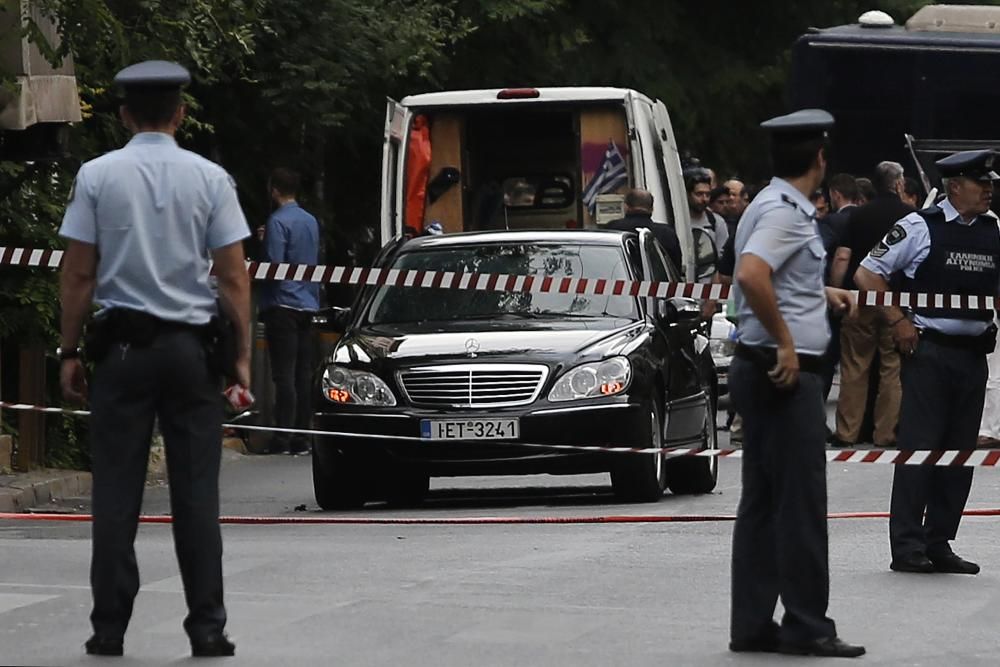 La Policía rodea el coche de Lucas Papademos tras la explosión del artefacto en el interior de su coche.