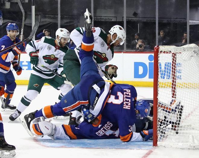 Adam Pelech # 3 y Thomas Greiss # 1 de los New York Islanders se defienden contra Jordan Greenway # 18 del Minnesota Wild durante el tercer período en el Barclays Center.