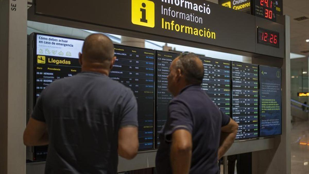 Dos pasajeros consultan un panel de vuelos.