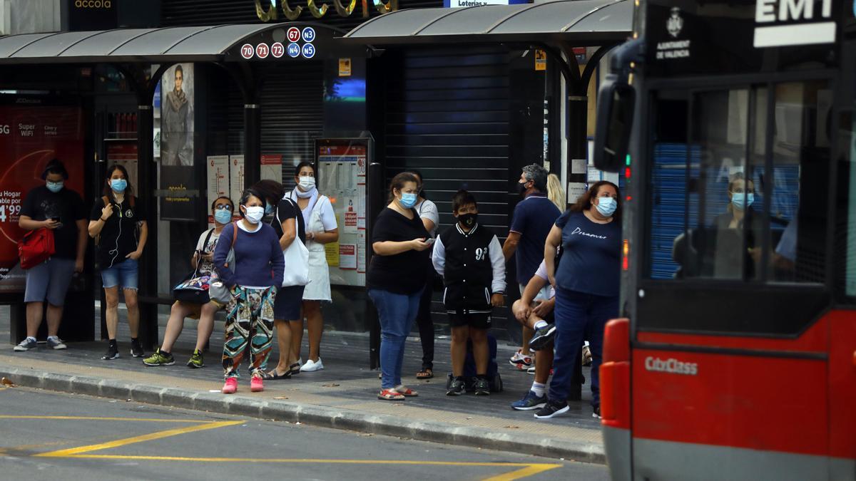 Un grupo de viajeros espera al autobús en la parada, durante la pandemia.