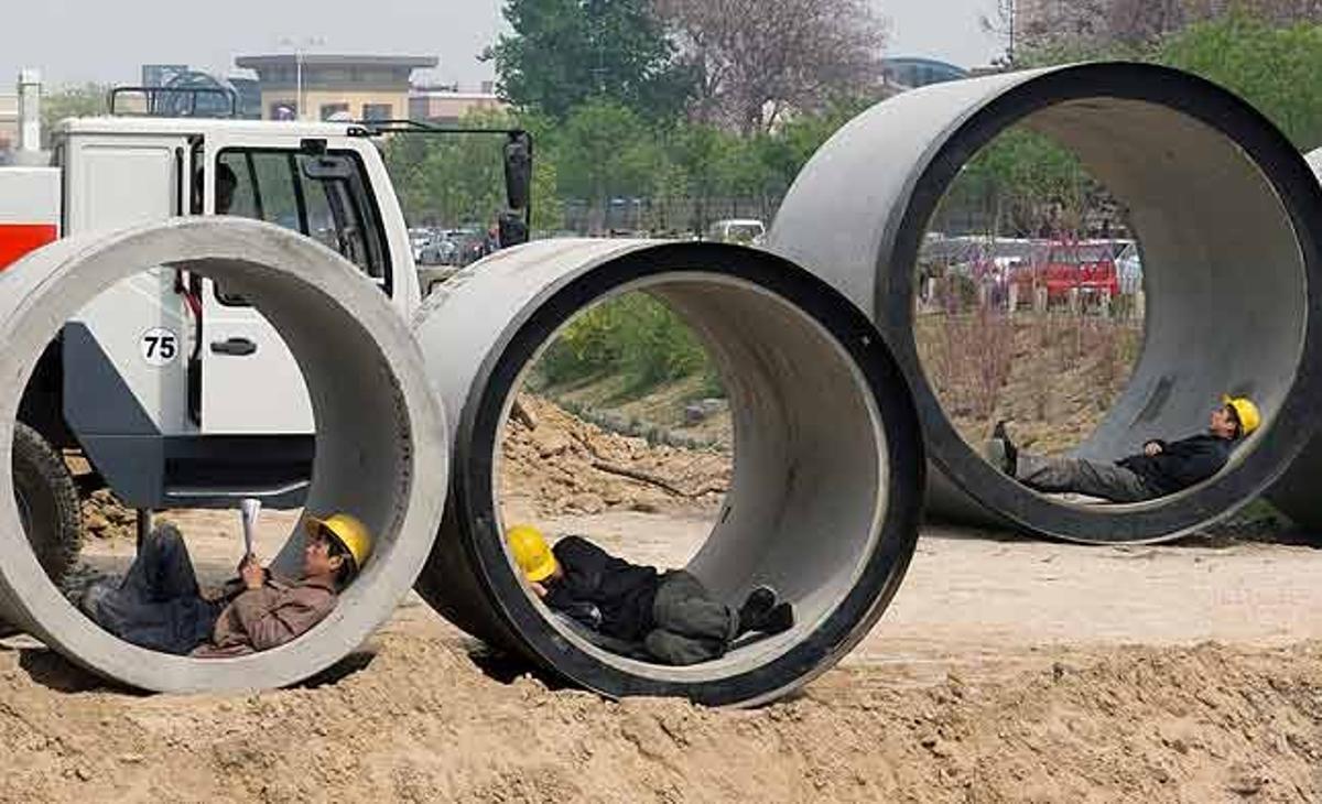 Obrers de la construcció disfruten d’un temps de descans dins una secció d’una canonada a prop d’un canal a Pequín (Xina).