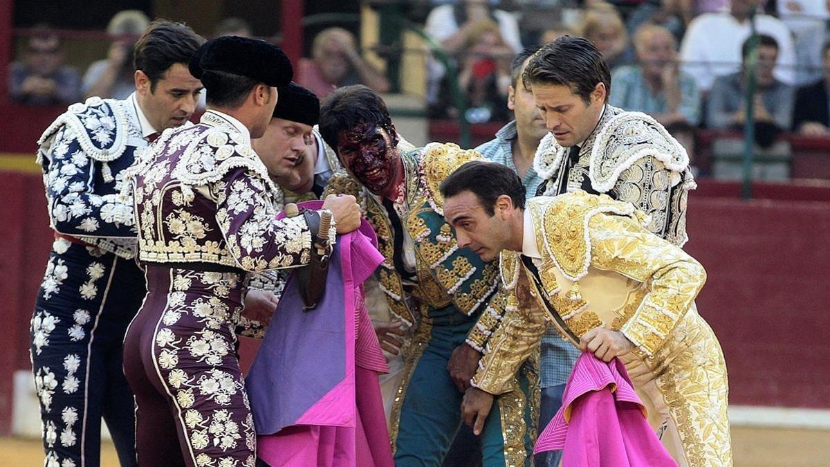 EL diestro, con la sangre del toro en la cara, es atendido tras la cogida.