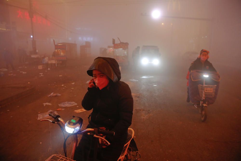 Varias personas de abren camino entre la niebla producida por la contaminación en Shengfang, China.