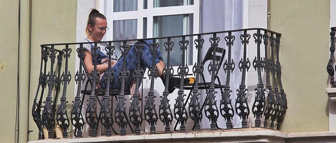 Una mujer lee en un balcón de València durante el confinamiento.