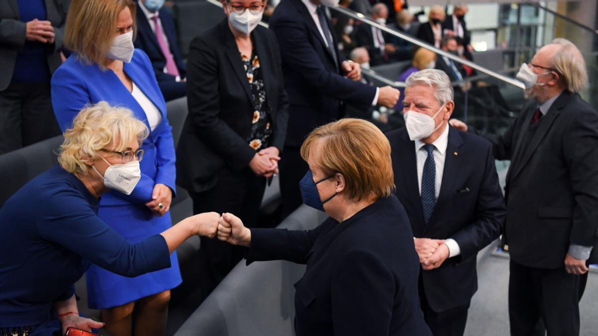 Merkel saluda a la ministra de Defensa, Christine Lambrecht, a su llegada al Parlamento para la votación del nuevo canciller