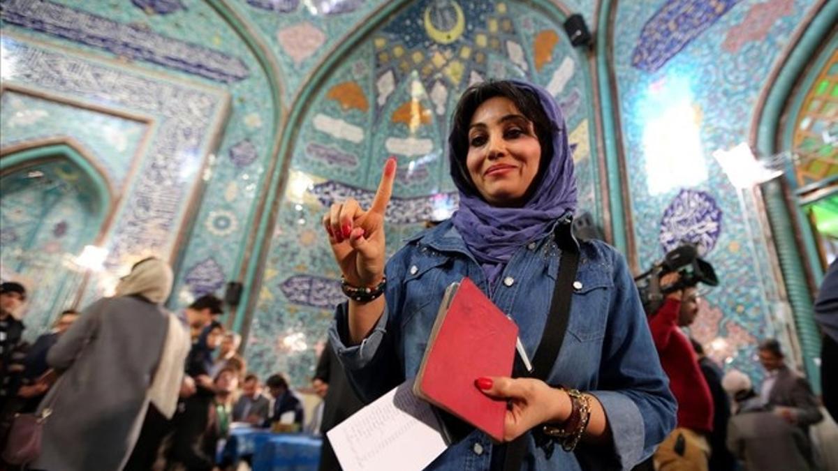 Una mujer iraní muestra su dedo entintado después de emitir su voto en un colegio electoral en Teherán, Irán.