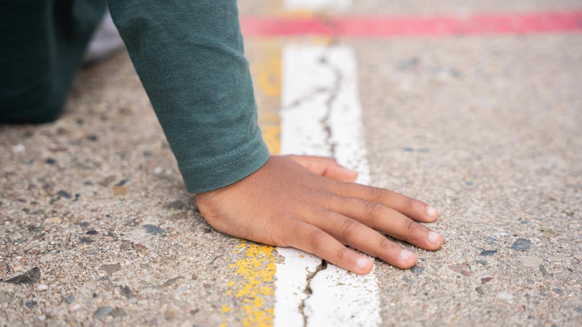 Mano de un niño en la pista de un colegio en Catalunya.