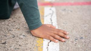 Mano de un niño en la pista de un colegio en Catalunya.