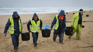 La Xunta eleva la alerta mientras los pellets se extienden y llegan hasta Francia. En la imagen, operarios retiran los pellets en la playa de O Vilar, en el parque natural de Corrubedo, A Coruña.