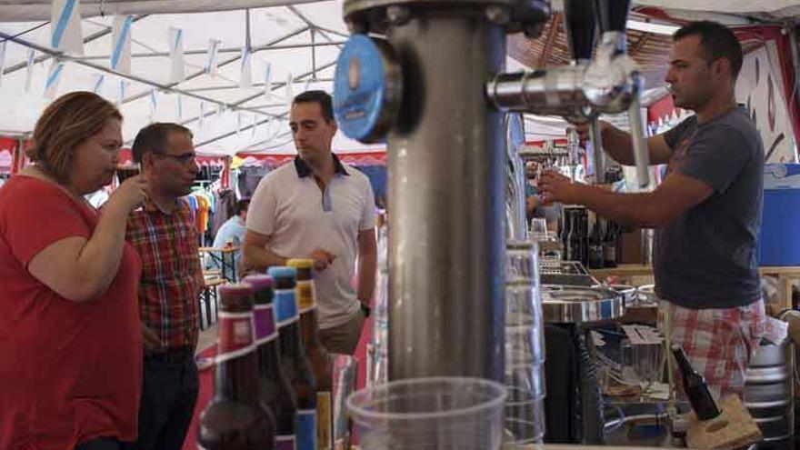 El alcalde, Luciano Huerga, y dos concejales prueban la cerveza artesanal en un puesto.